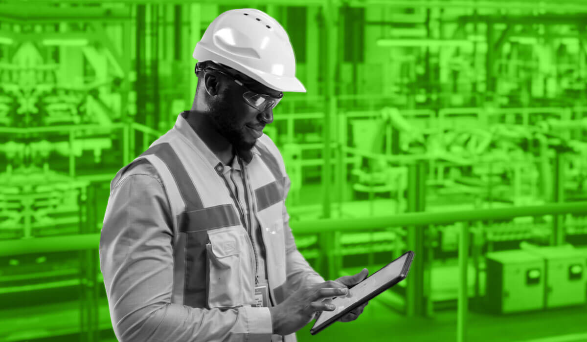 A construction worker in a hard hat and safety glasses is operating a tablet.