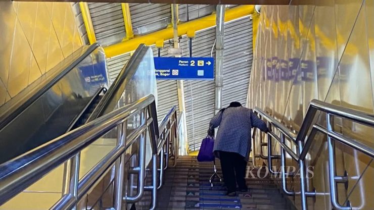 image of woman struggling to walk up set of stair because escalator is broken