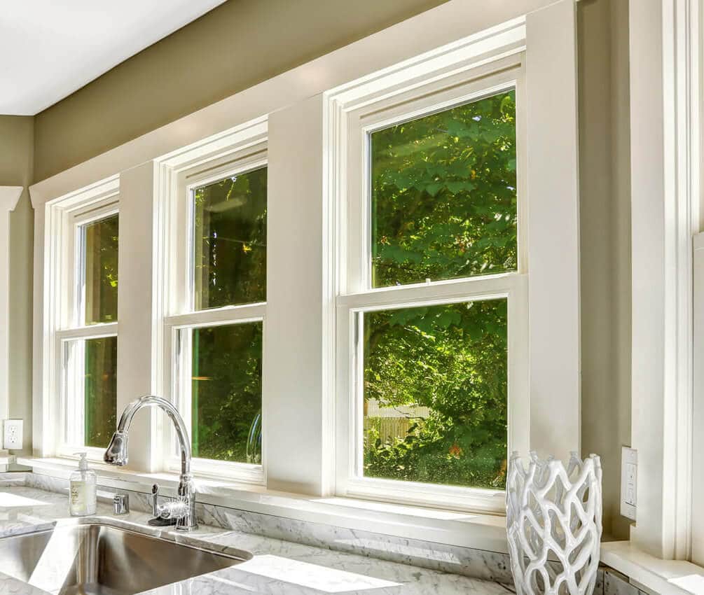 A series of three double-hung windows seen from the interior of a kitchen.