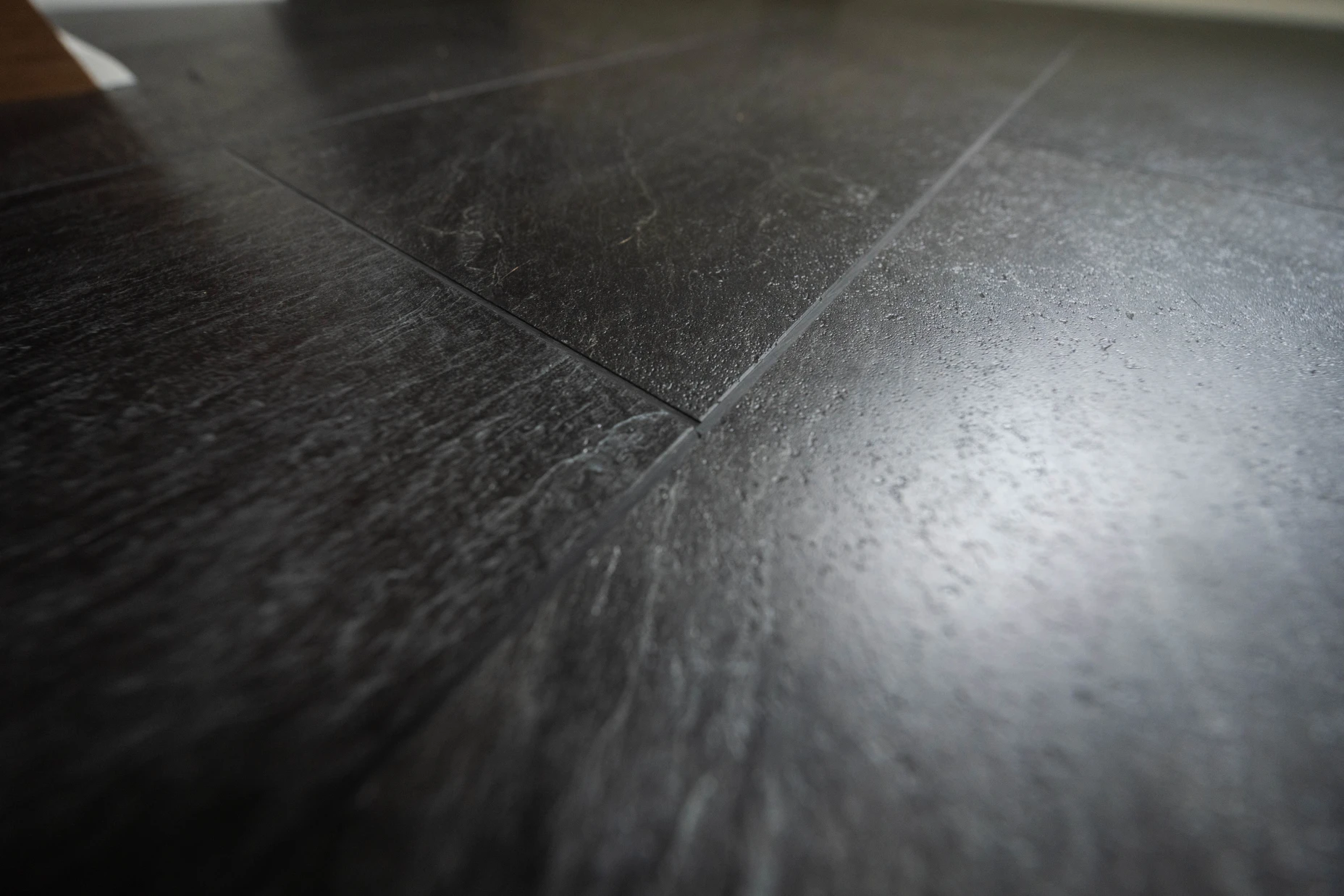 A close up image of black tile vinyl flooring.