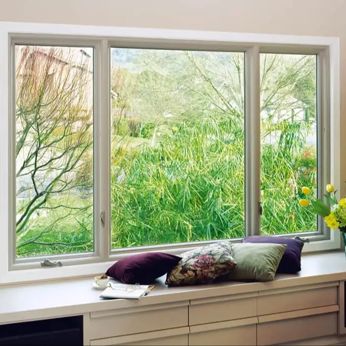 A large picture window in a residential home looking out on a large bush.