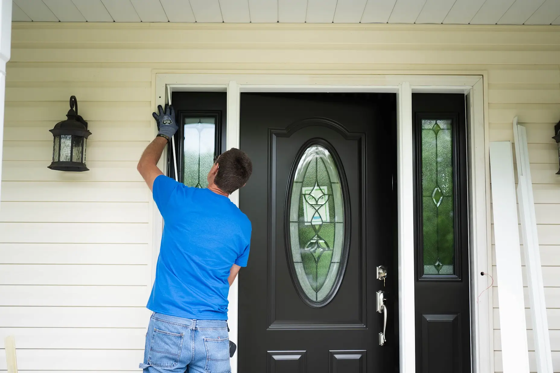 A man installing a door onto a home.