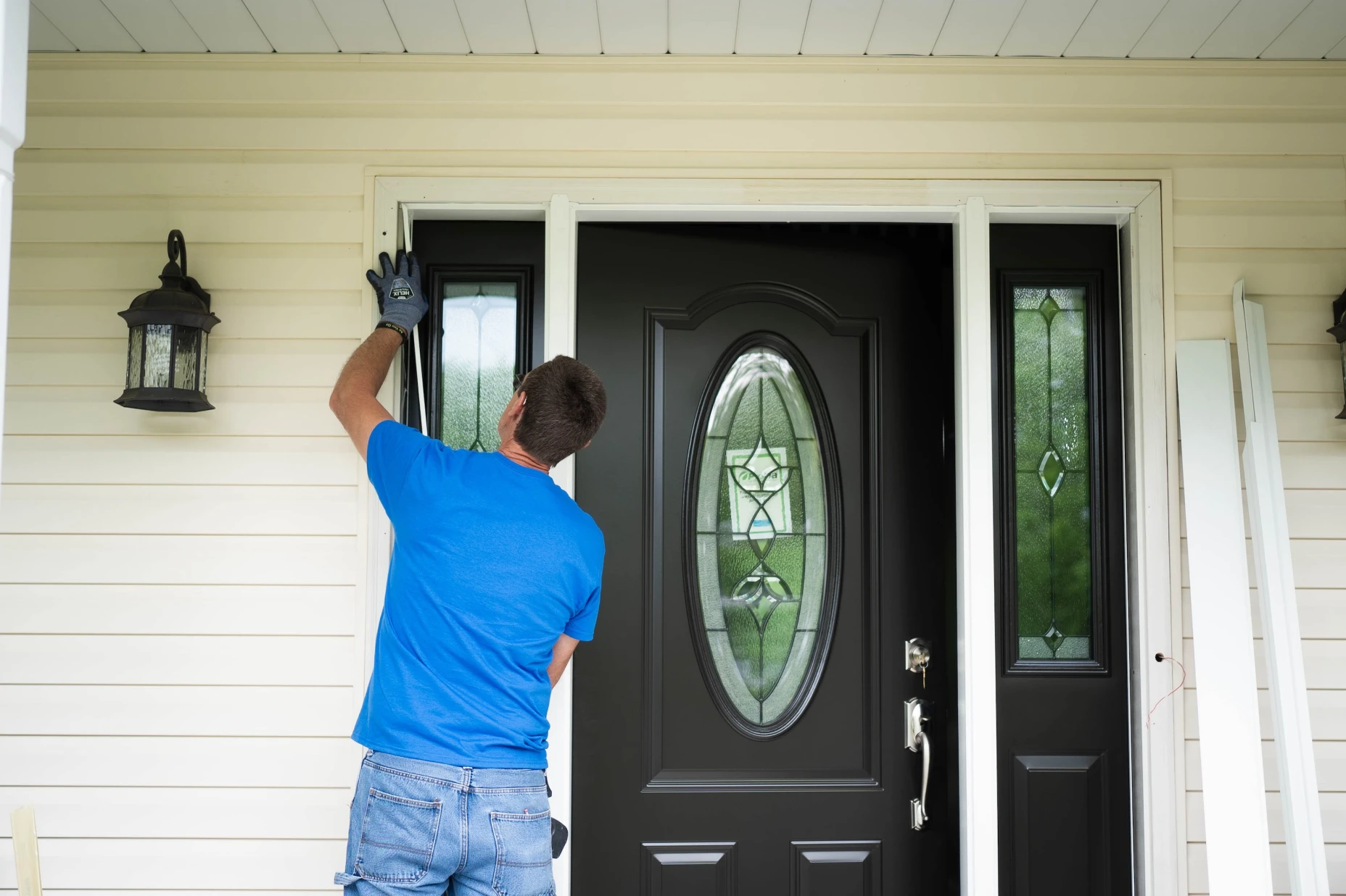 A man installing a door onto a home.