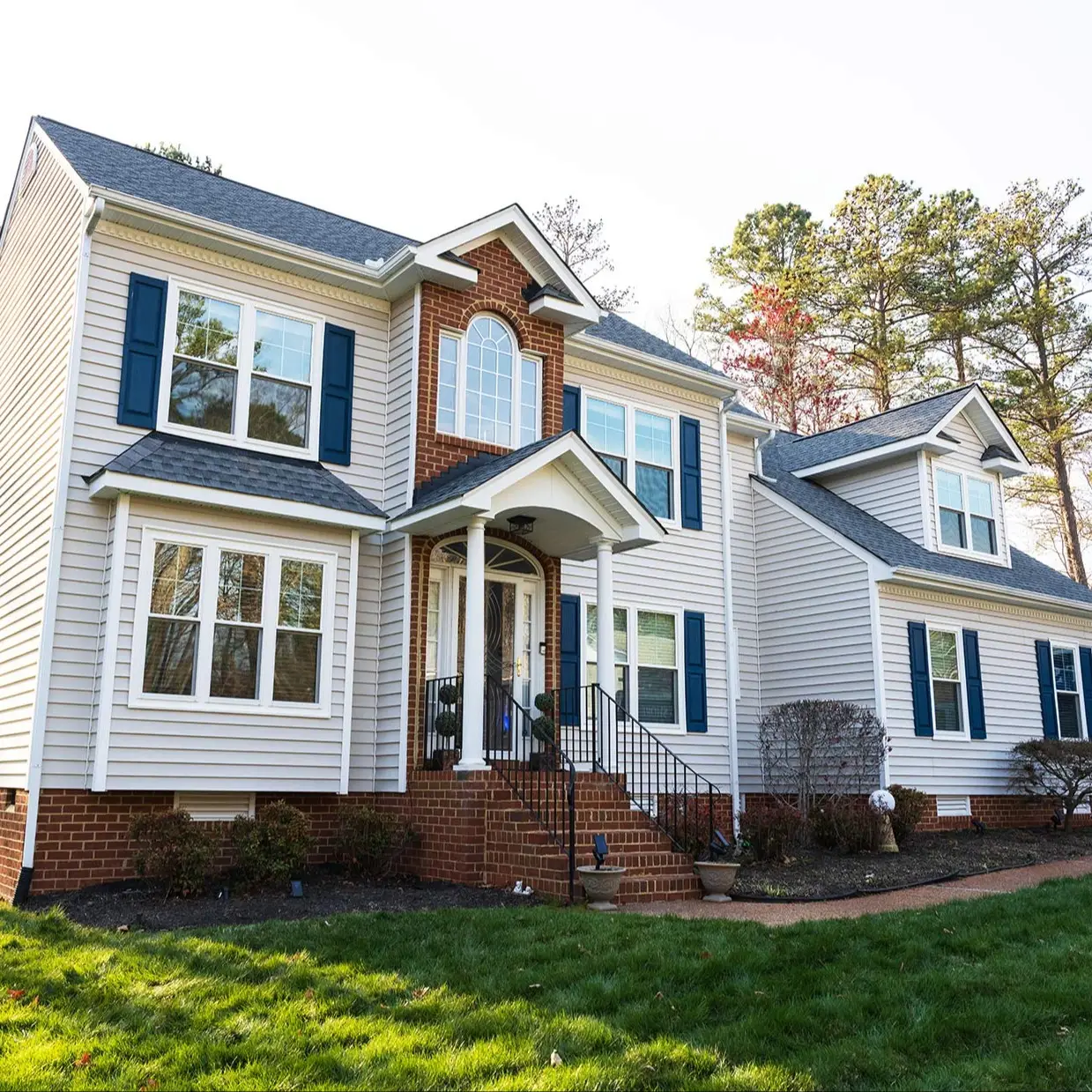 A suburban home with a brick entryway and several double hung windows replaced by West Shore Home.