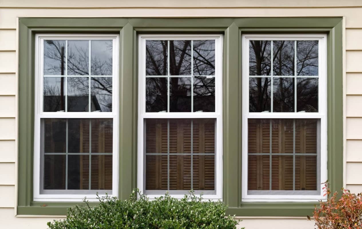 Three double-hung windows with green vinyl window frames.