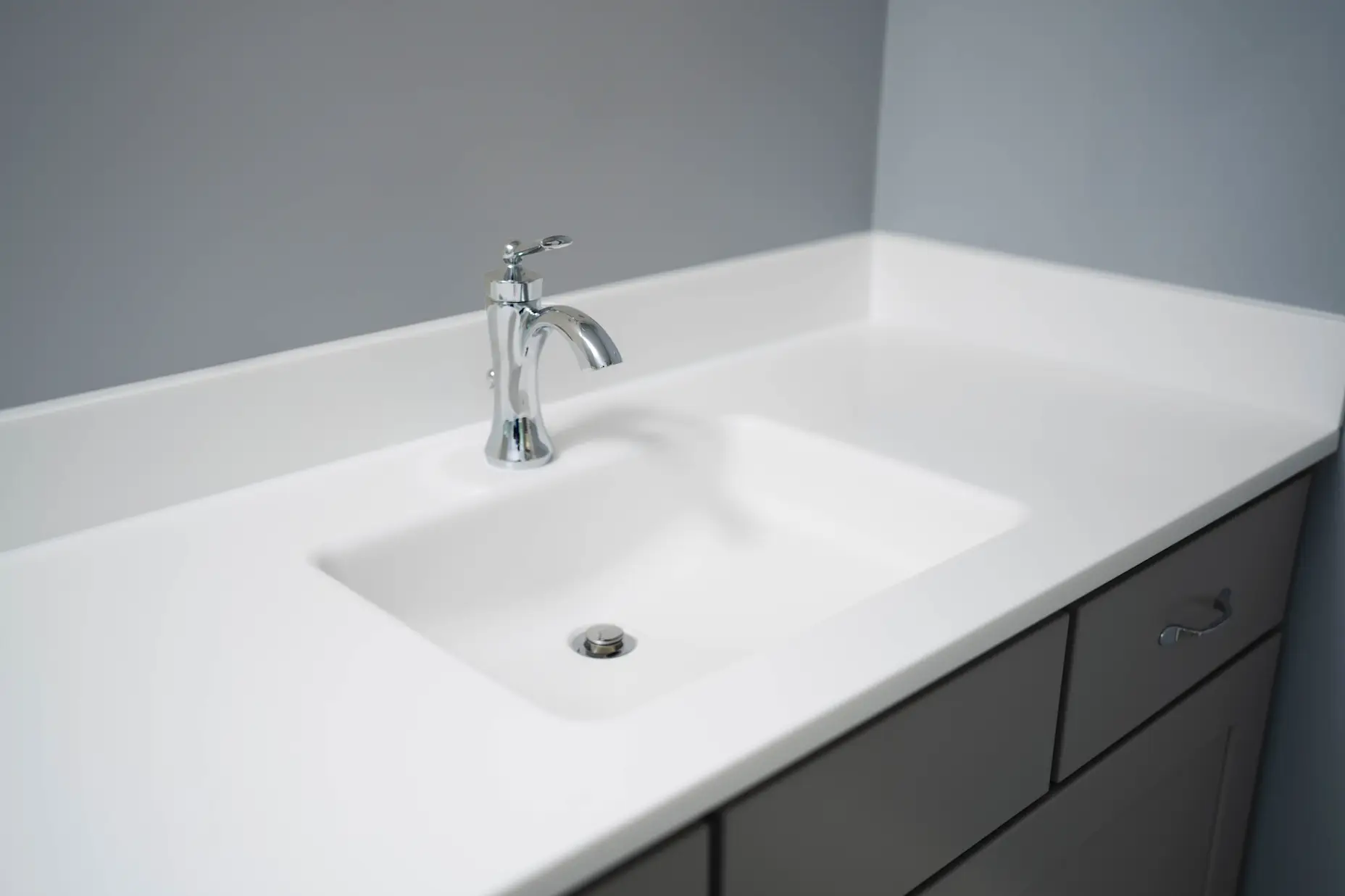 A close up image of a white countertop with silver faucet.