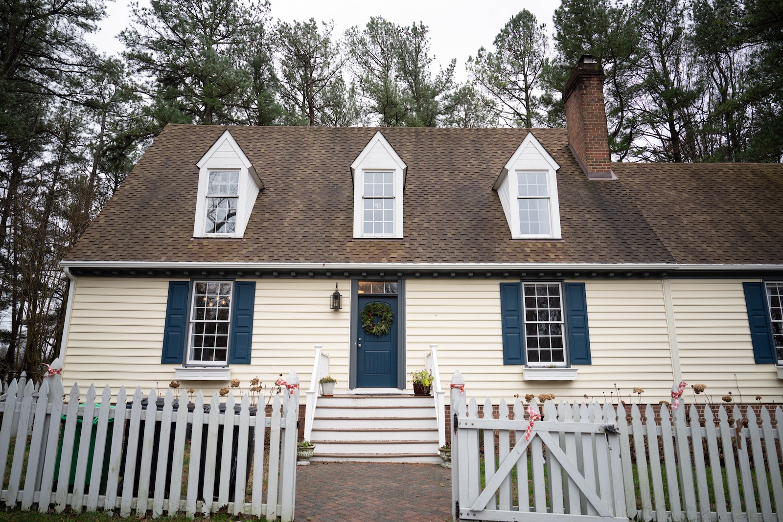 A two-story house in the woods with large dormer windows.