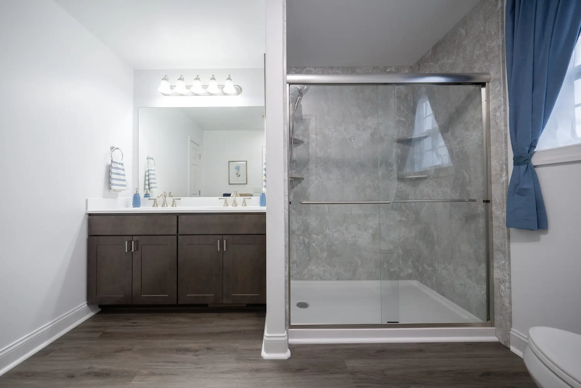 A grey bathroom with a walk-in shower and dark vanity.