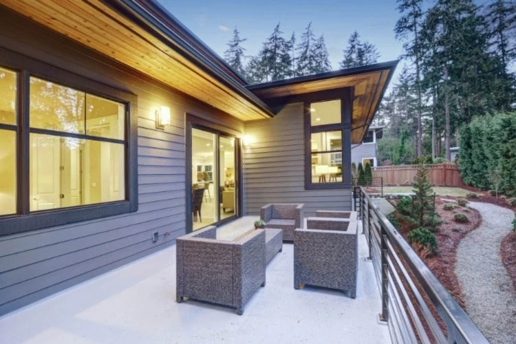 Black patio door on a home with black siding and a modern patio.