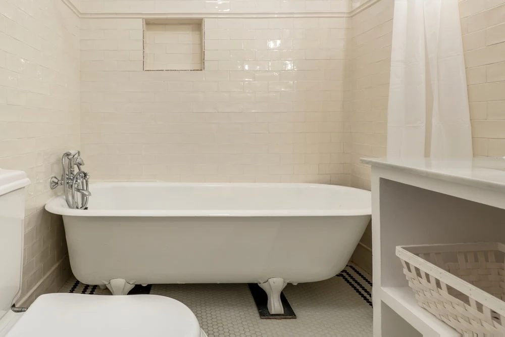 A large, white clawfoot tub in a sparse tile bathroom.