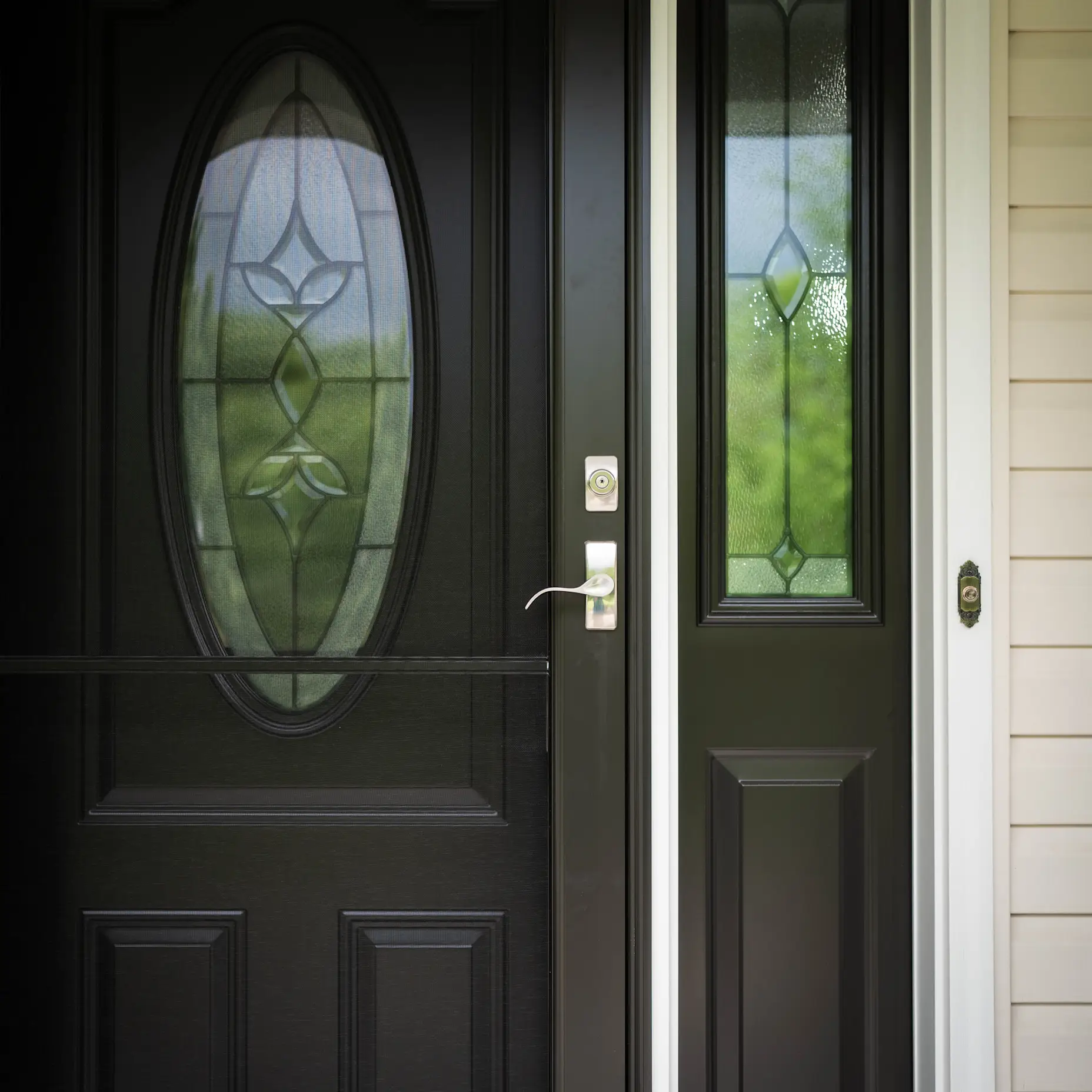 A black storm door on a black front door with silver hardware.