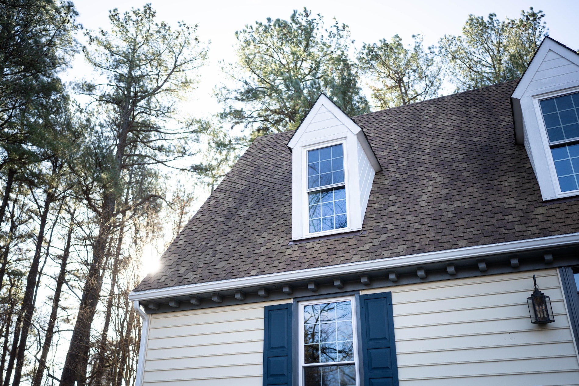 A two-story house in the woods with large dormer windows.