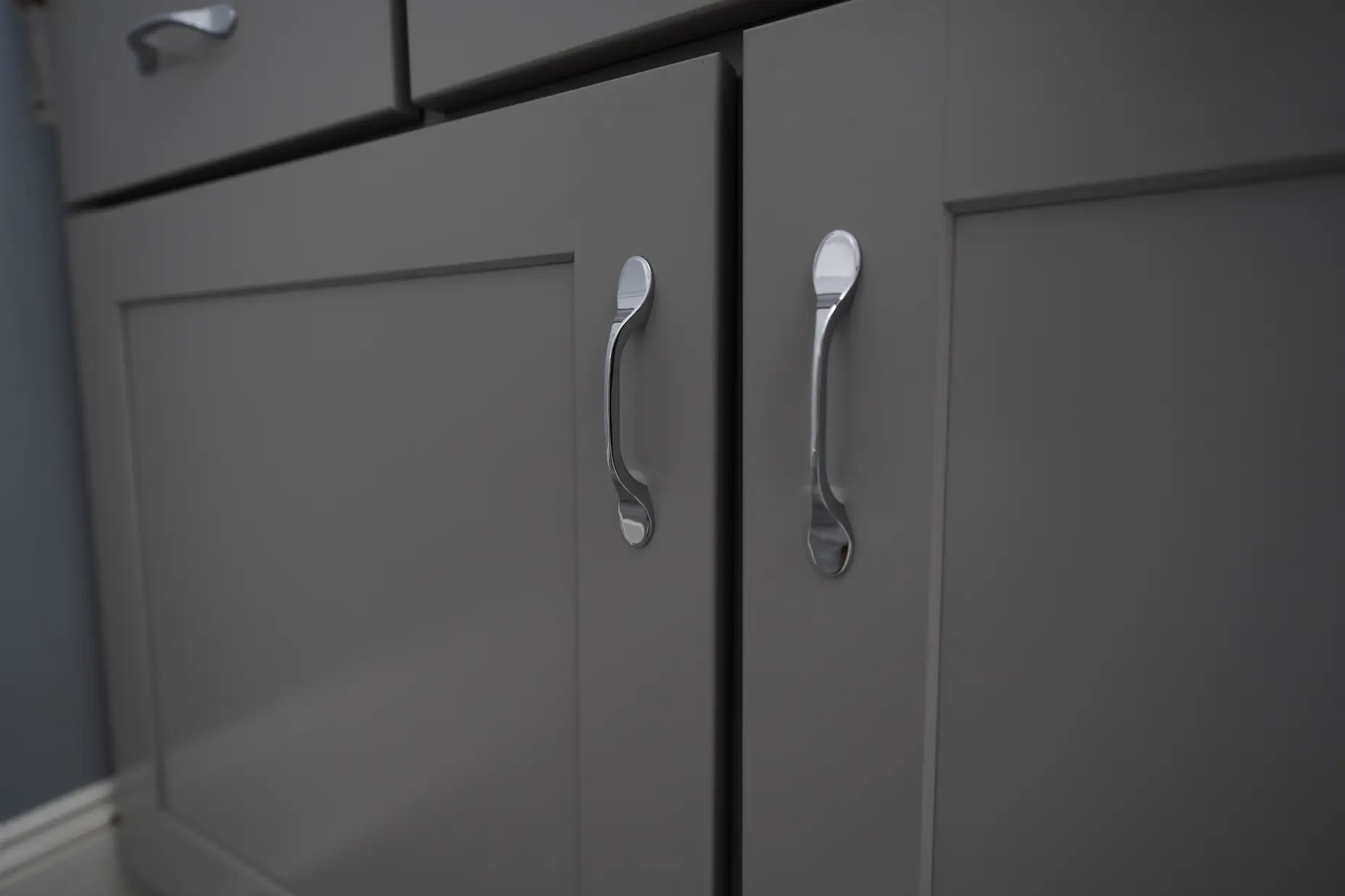 A close up image of a grey vanity with silver hardware.