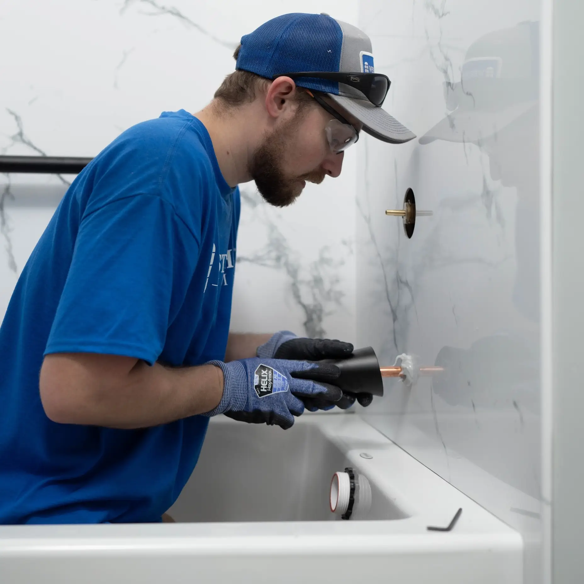 A man installing a faucet into a bathtub wall. 