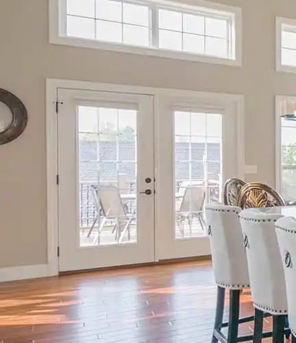 White french doors seen from a lavishly decorated, spacious kitchen.