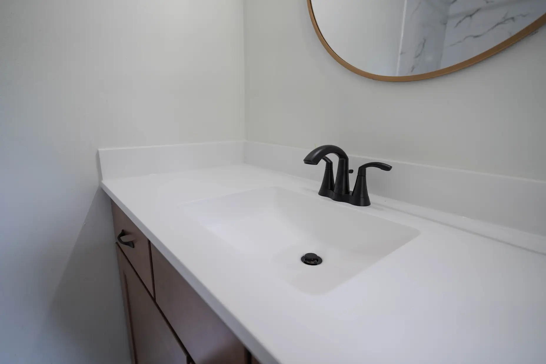 An above angle photo of a white countertop with black faucet.