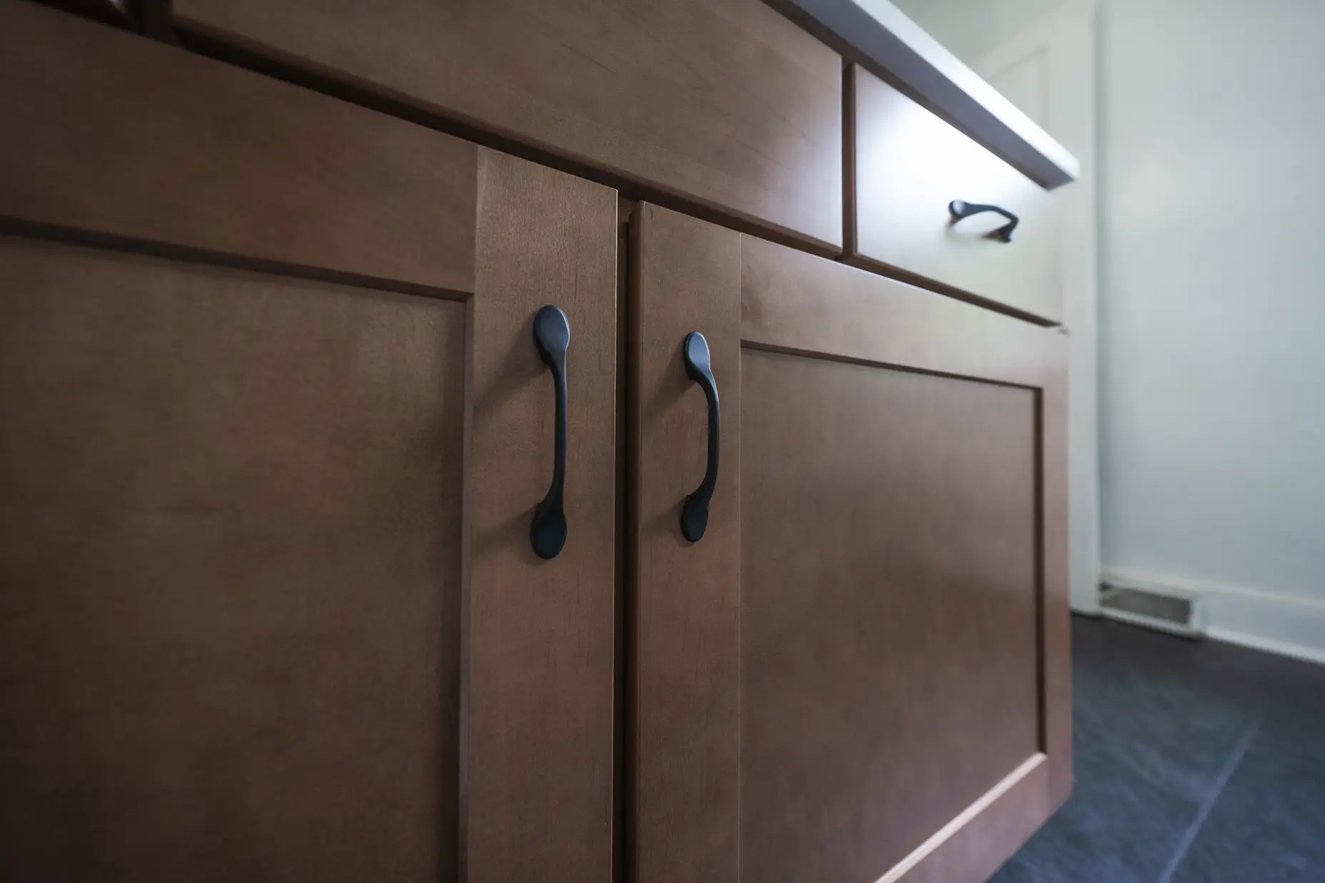 A close up shot of a dark wood vanity with bronze hardware.