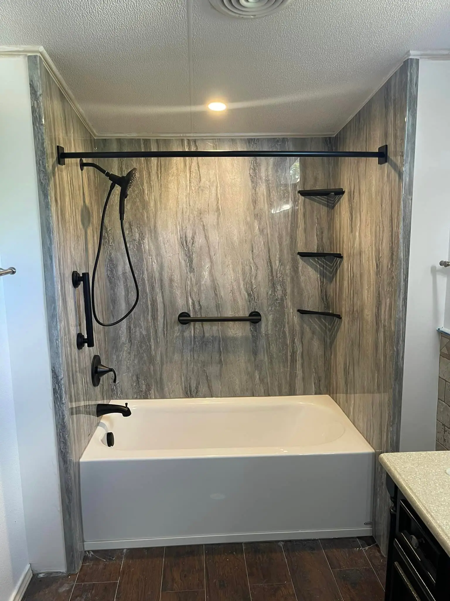 A neutral earth tone bathtub shower combo with black matte fixtures.