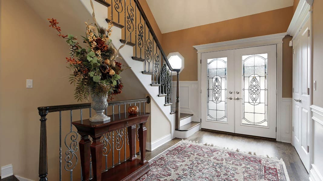 A large foyer with a grand staircase and a large entryway with French doors.