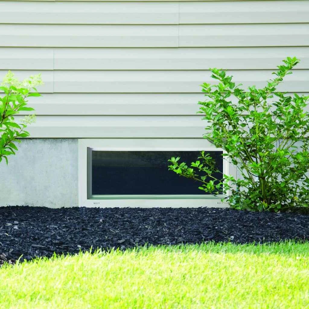 A hopper window placed in the basement of a home overlooking the yard.