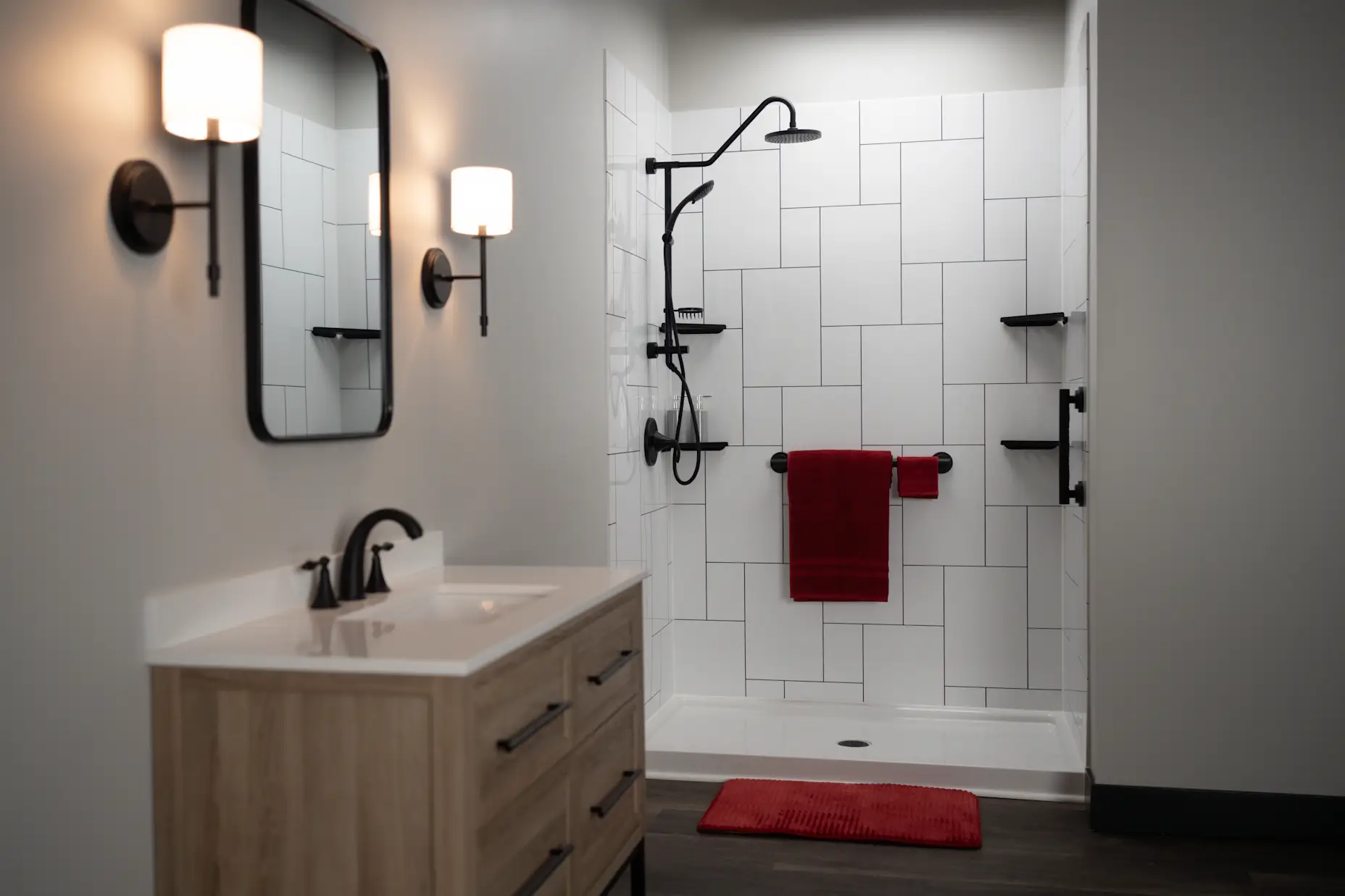 A black and white acrylic tile shower with red accents and black matte shower fixtures.