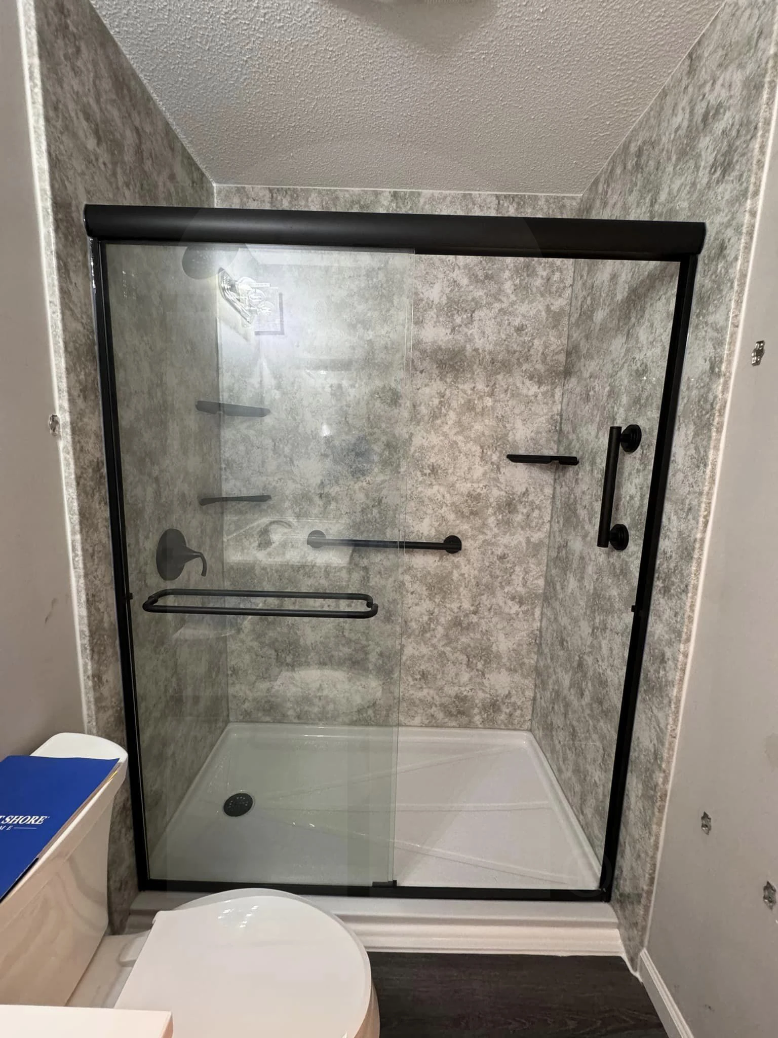 A newly-installed walk-in shower with a sliding glass door.