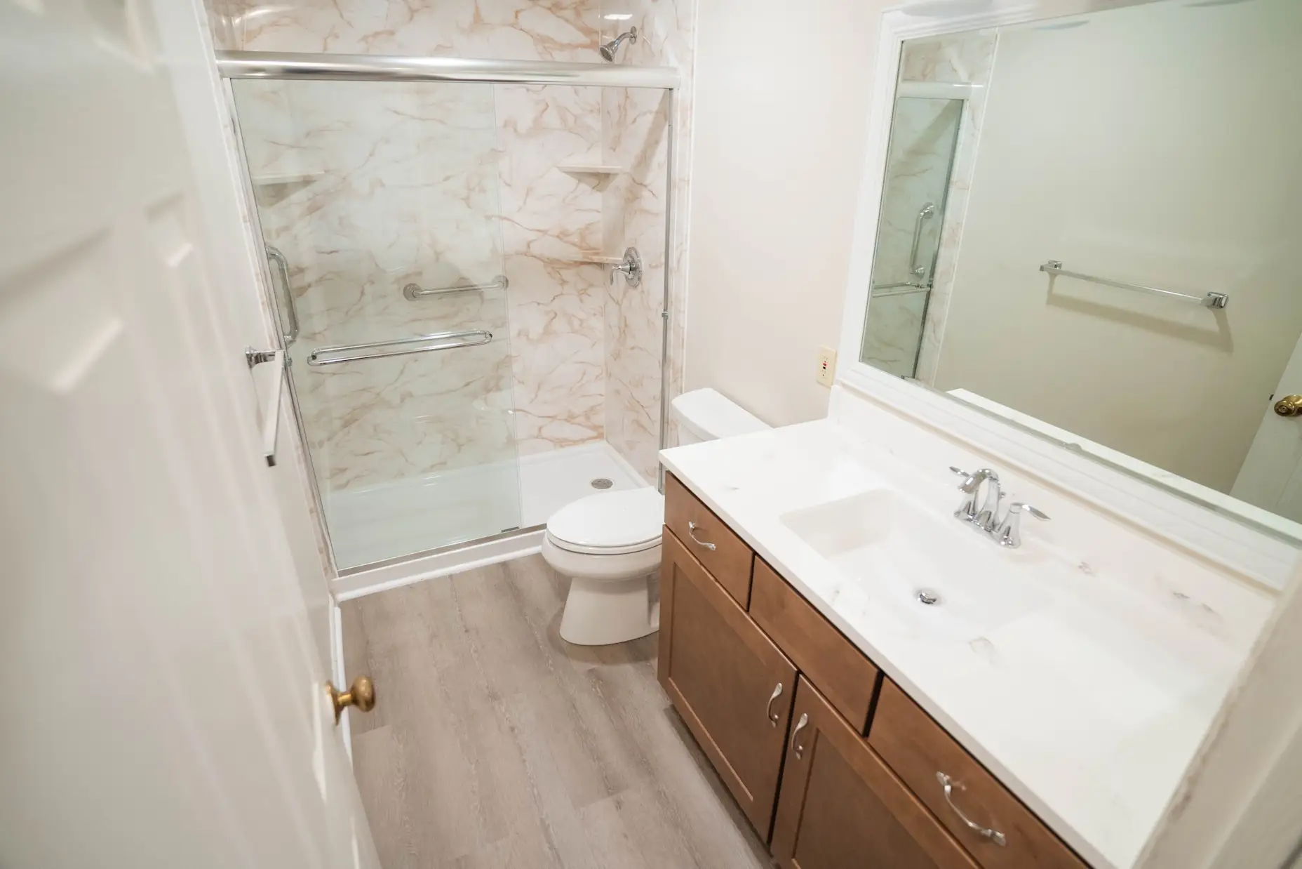 An image of a bathroom with a walk-in shower, vanity, and toilet.