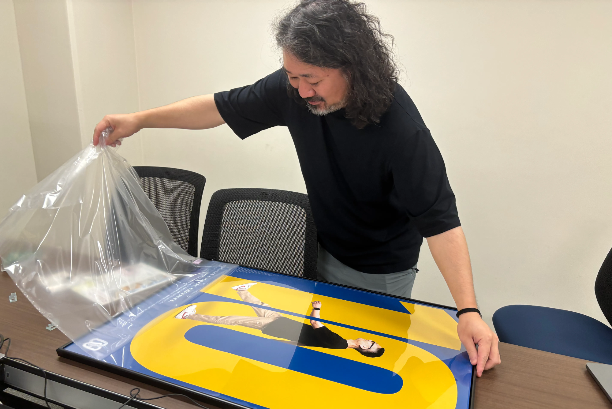 mojaさんがポスターを慎重に額装している様子