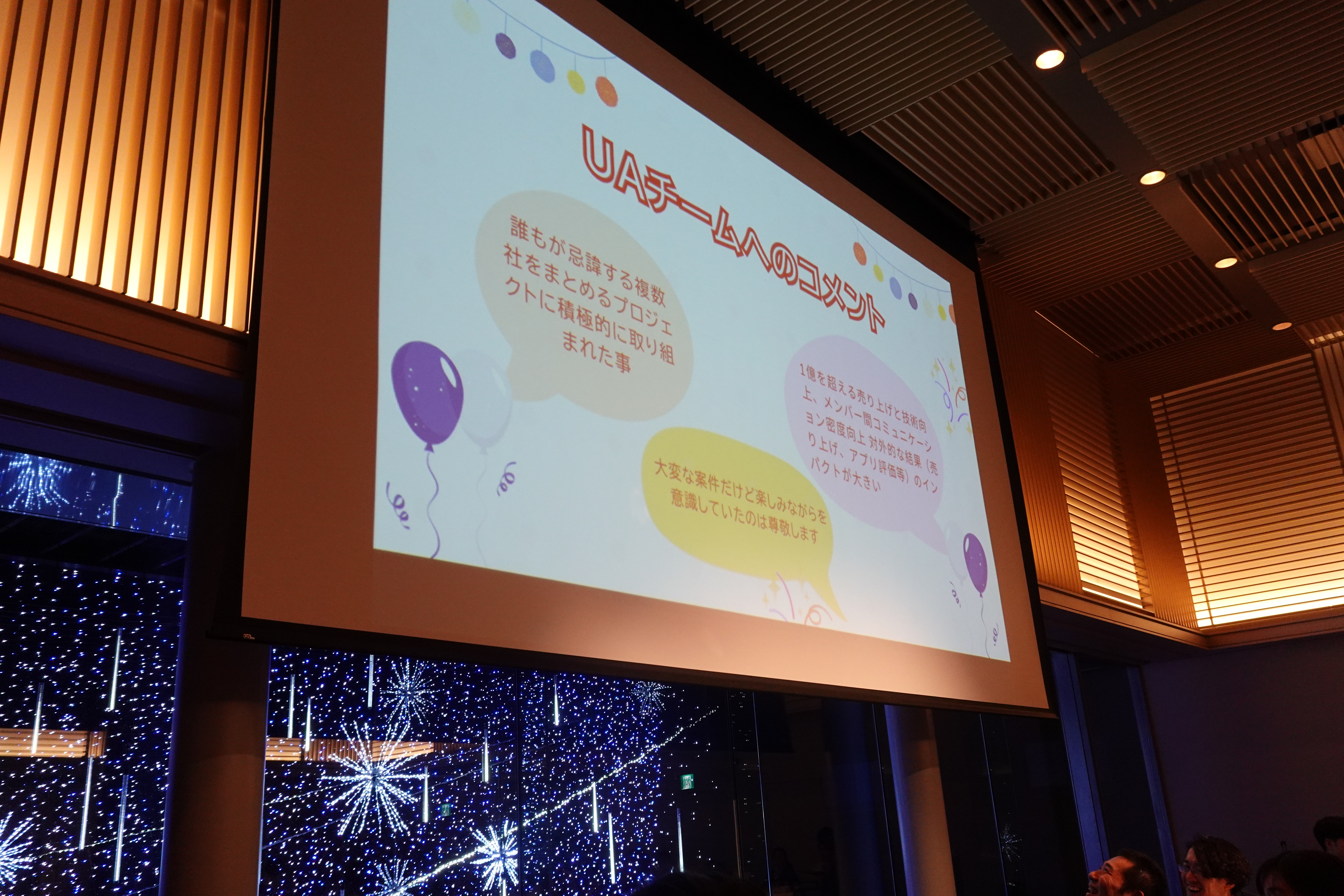 表彰内容の一部がスクリーンに映し出されている様子