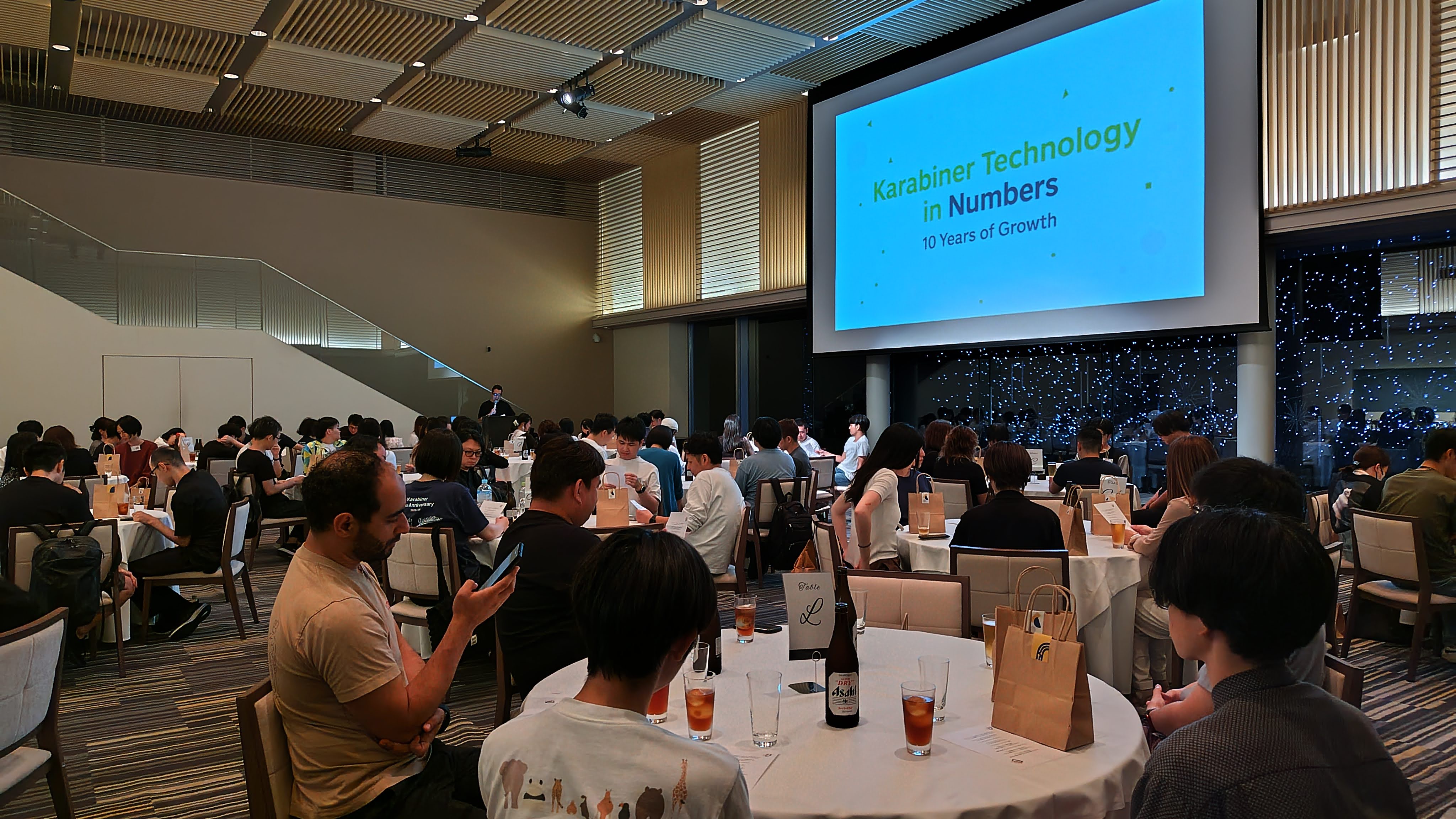 スクリーンに映し出される「数字で見るカラビナテクノロジー」の写真