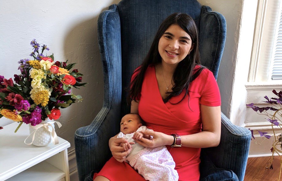 A very tired new mama holding her little precious and happy with her beautiful flower bouquet.