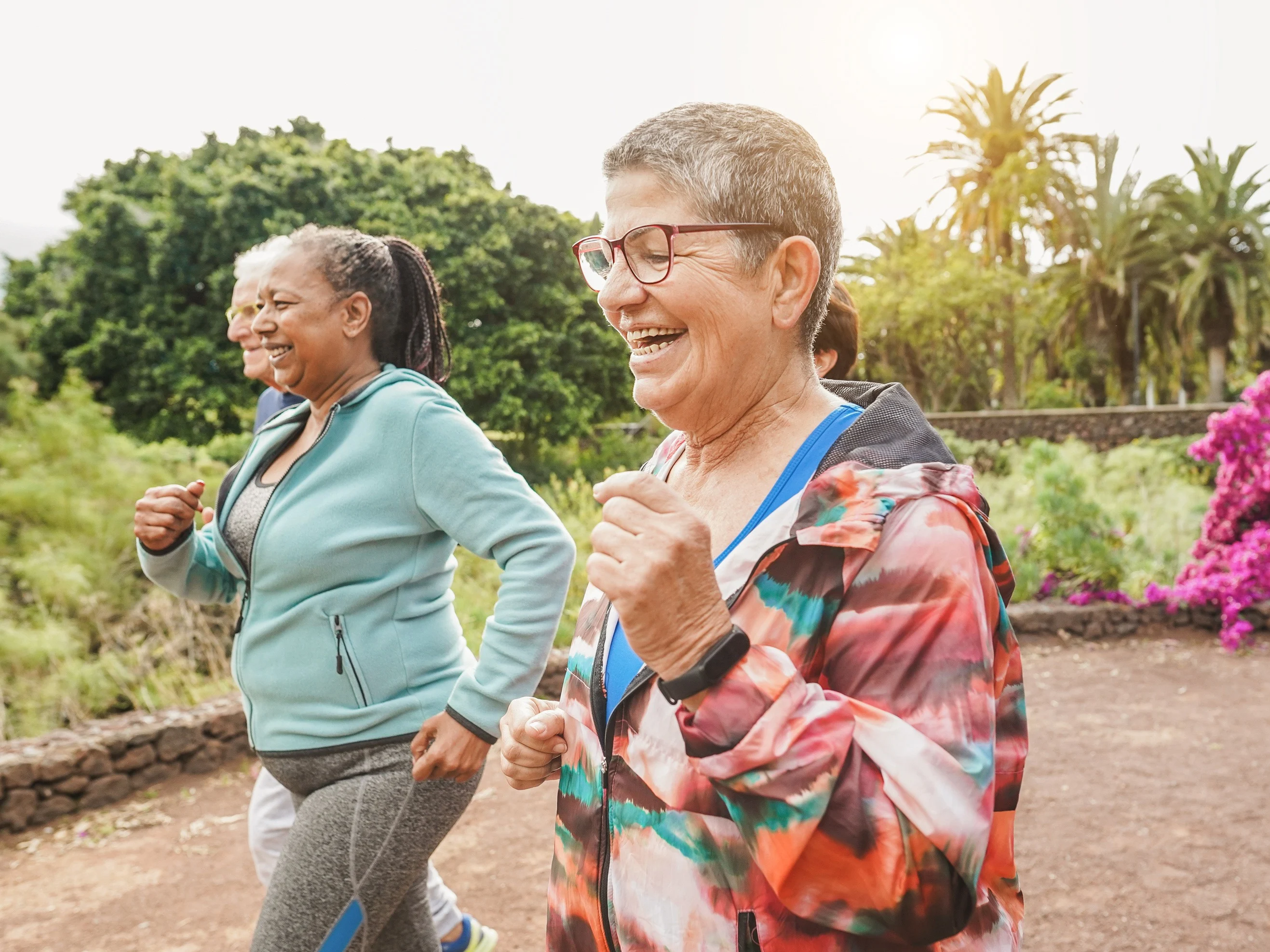 A group of two white, one Latina, and one African American senior women exercising and laughing together.