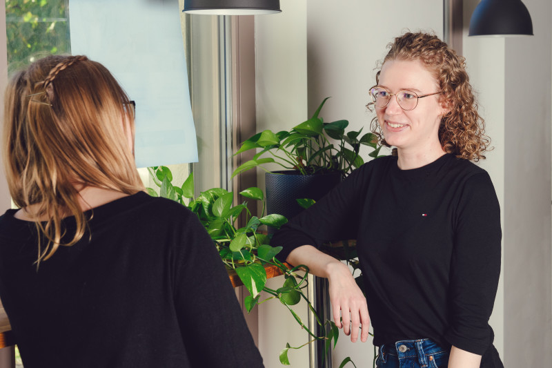 Two team members talking in our Berlin office, plants are to be seen in the background.