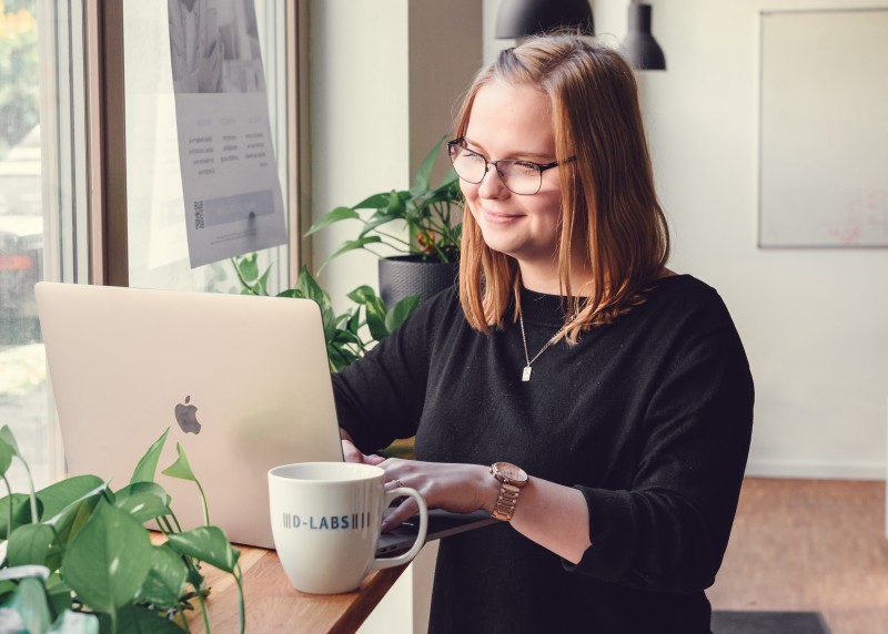 User Researcher Stella arbeitet lächelnd am Laptop in unserem Berliner Office.