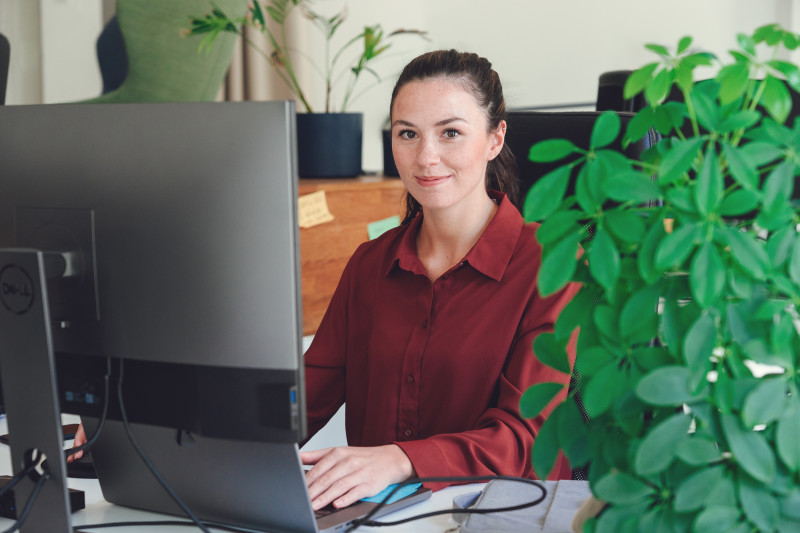 A woman working on a laptop with a friendly smile.