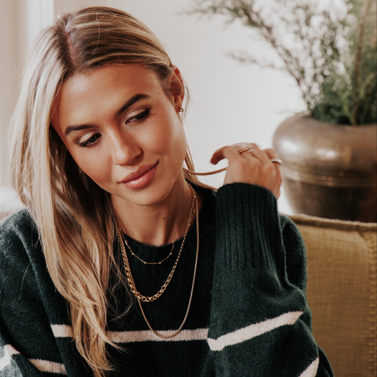 Model wearing three gold chain necklaces