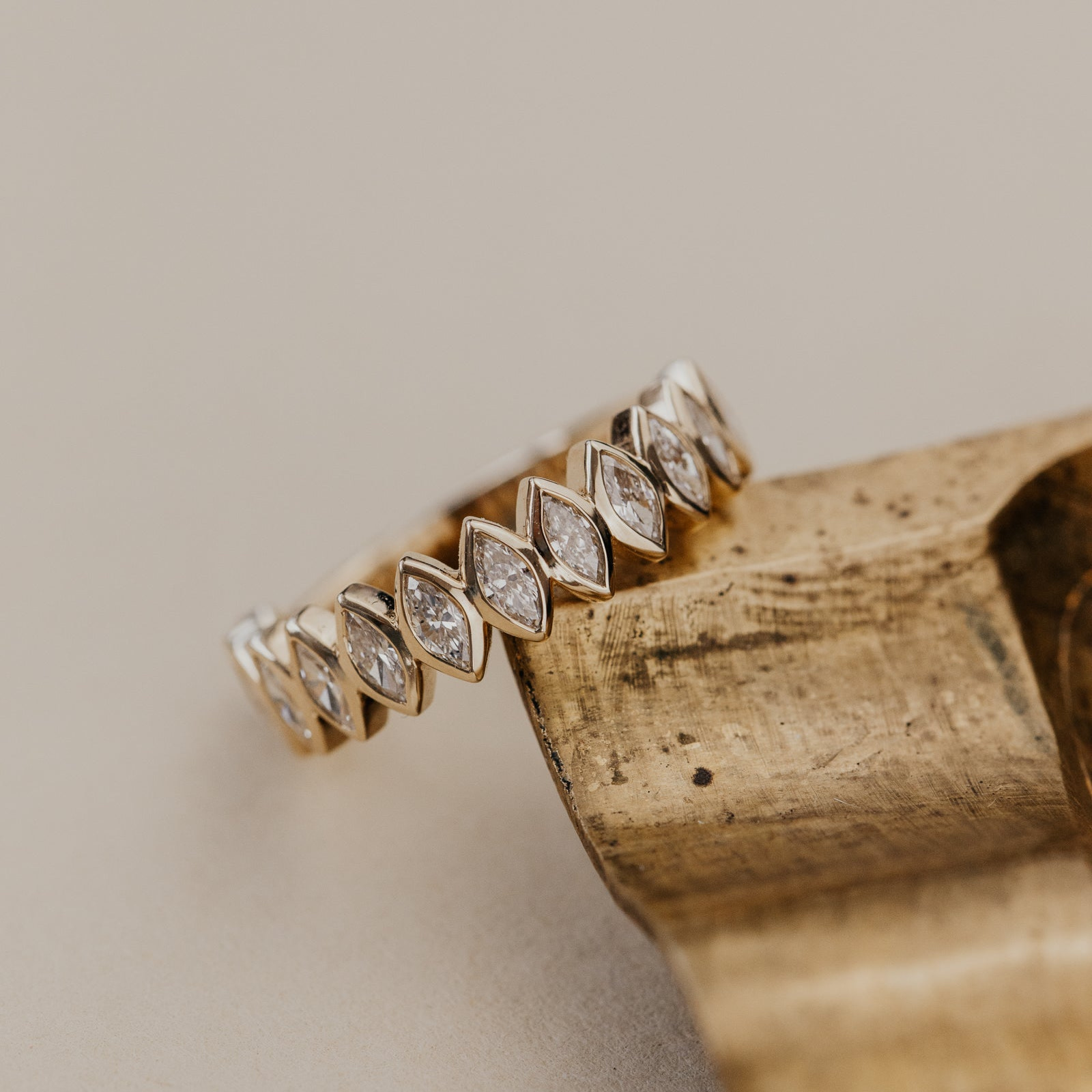 The Marlowe marquise diamond wedding band on a wooden block against a beige backgroud.