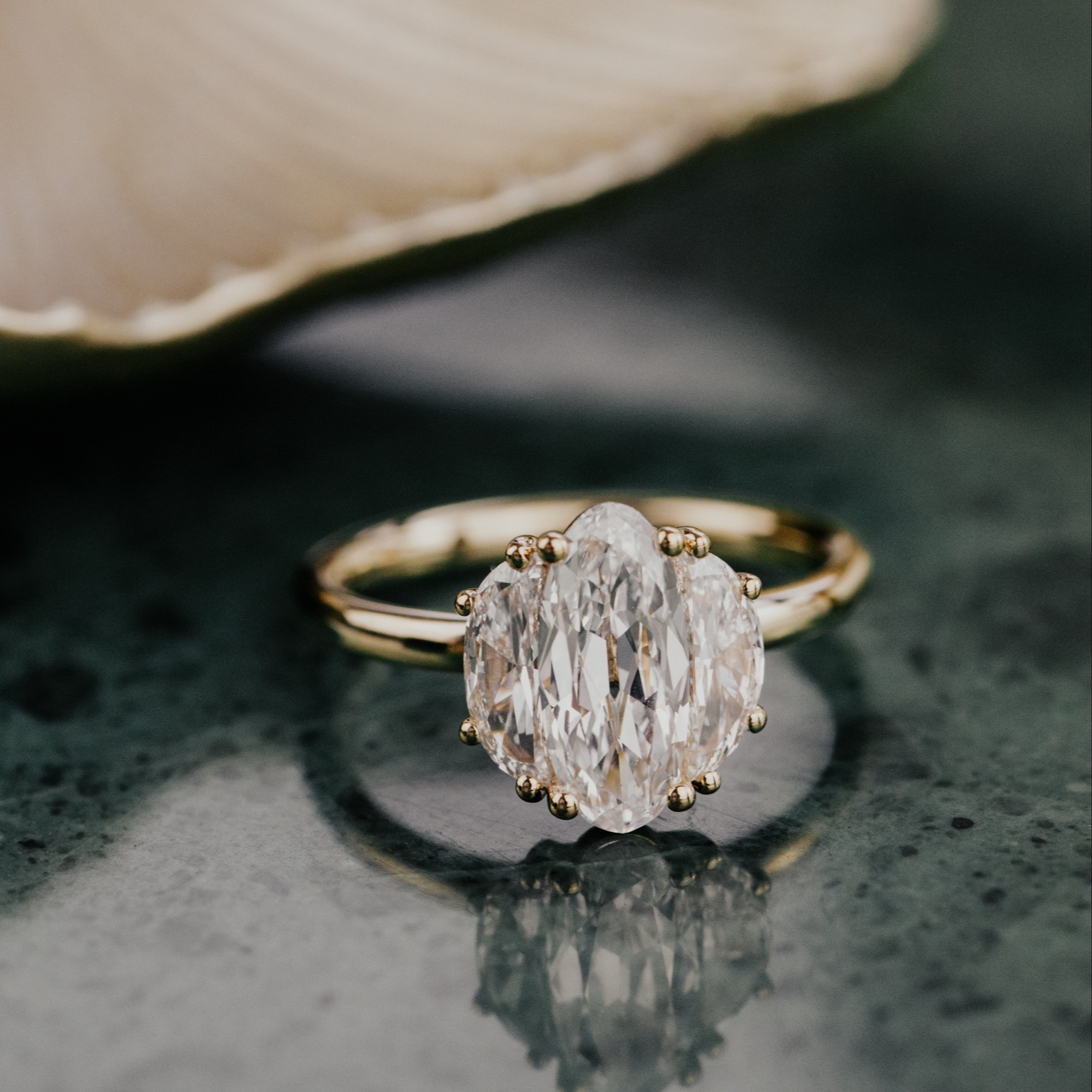 The Thalia 1.25 ct Elongated Oval Diamond Ring on a green surface