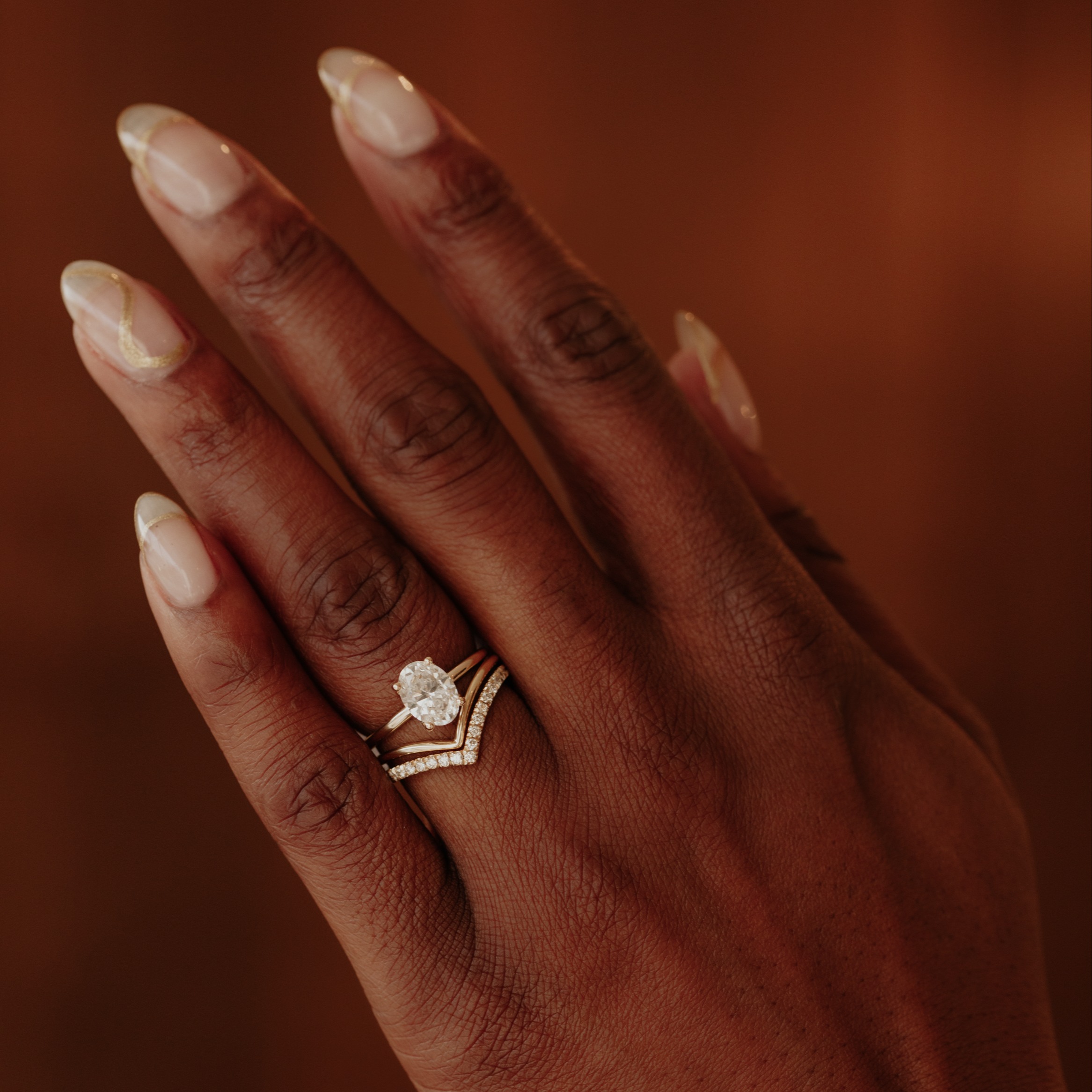 Model wearing the Maeve oval diamond engagement rings stacked with a gold tracer and a diamond tracer wedding band. 