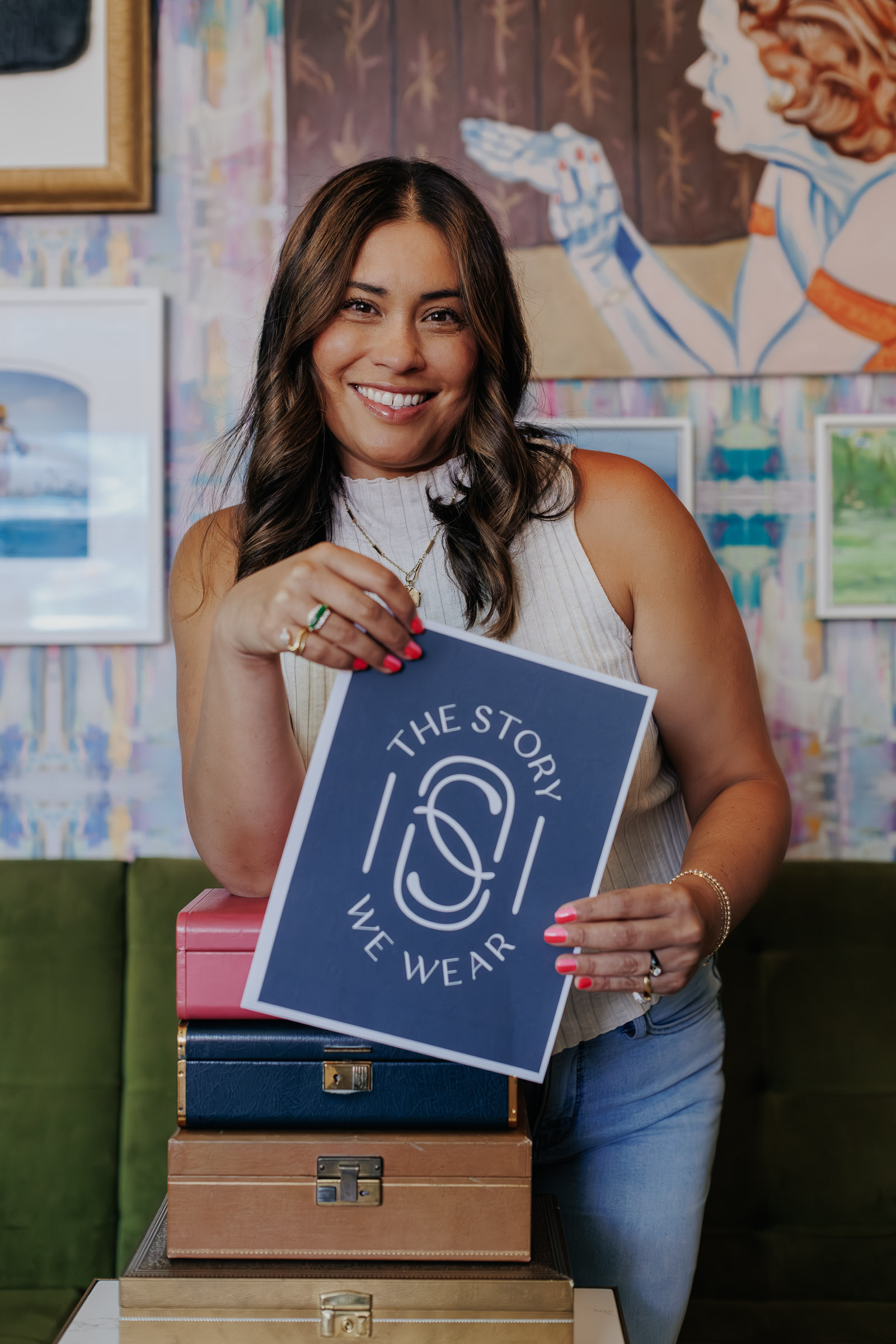 Photo of Sarah holding a sign with The Story We Wear logo