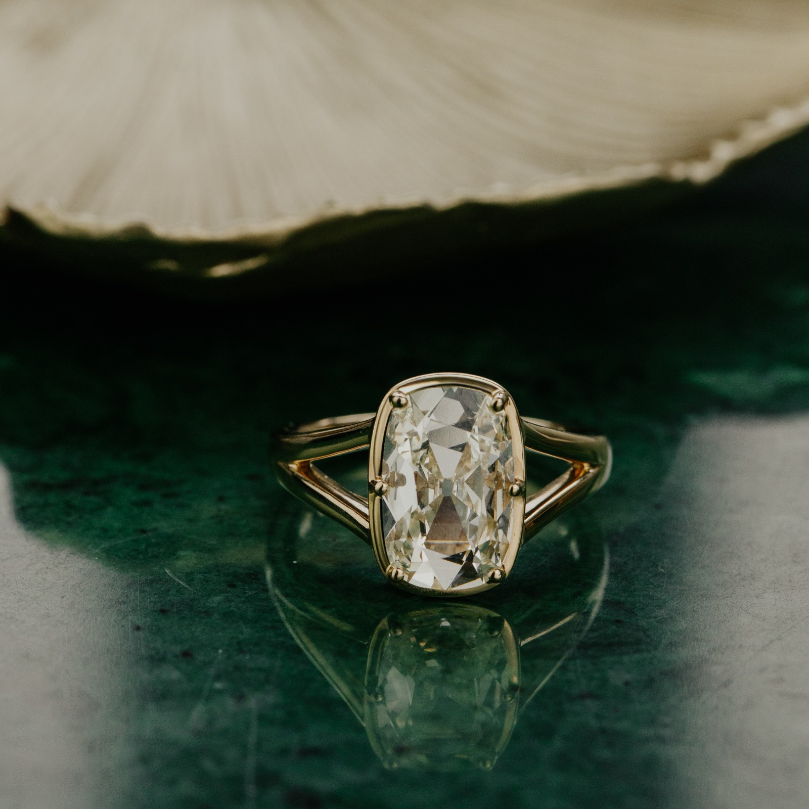 14k yellow gold ring with a one-of-a-kind 2.51 ct elongated old mine cut natural diamond set in six prongs with a split shank on a green surface.