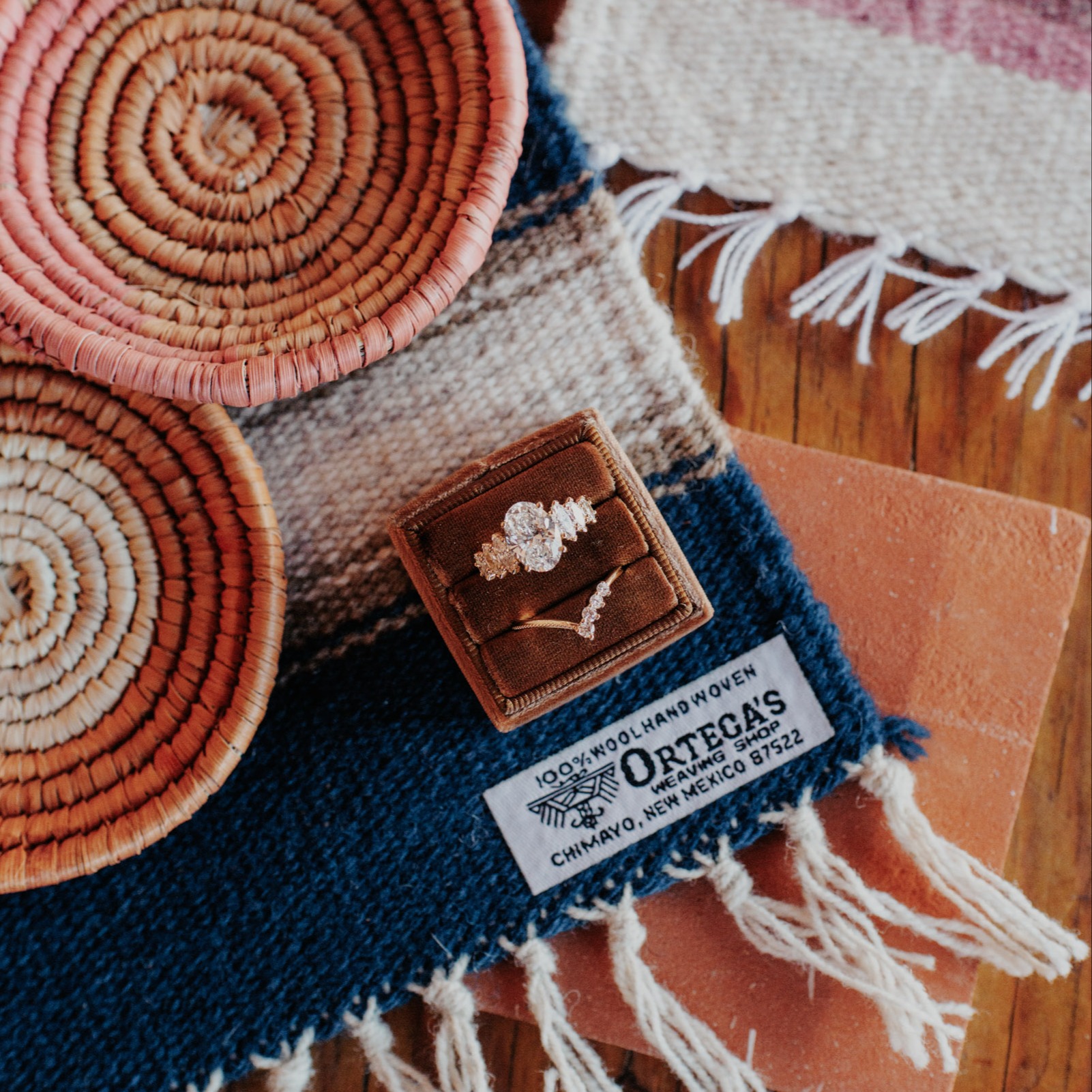 The Ortega diamond engagement ring in a brown velvet box placed on top of woven Ortega blankets.