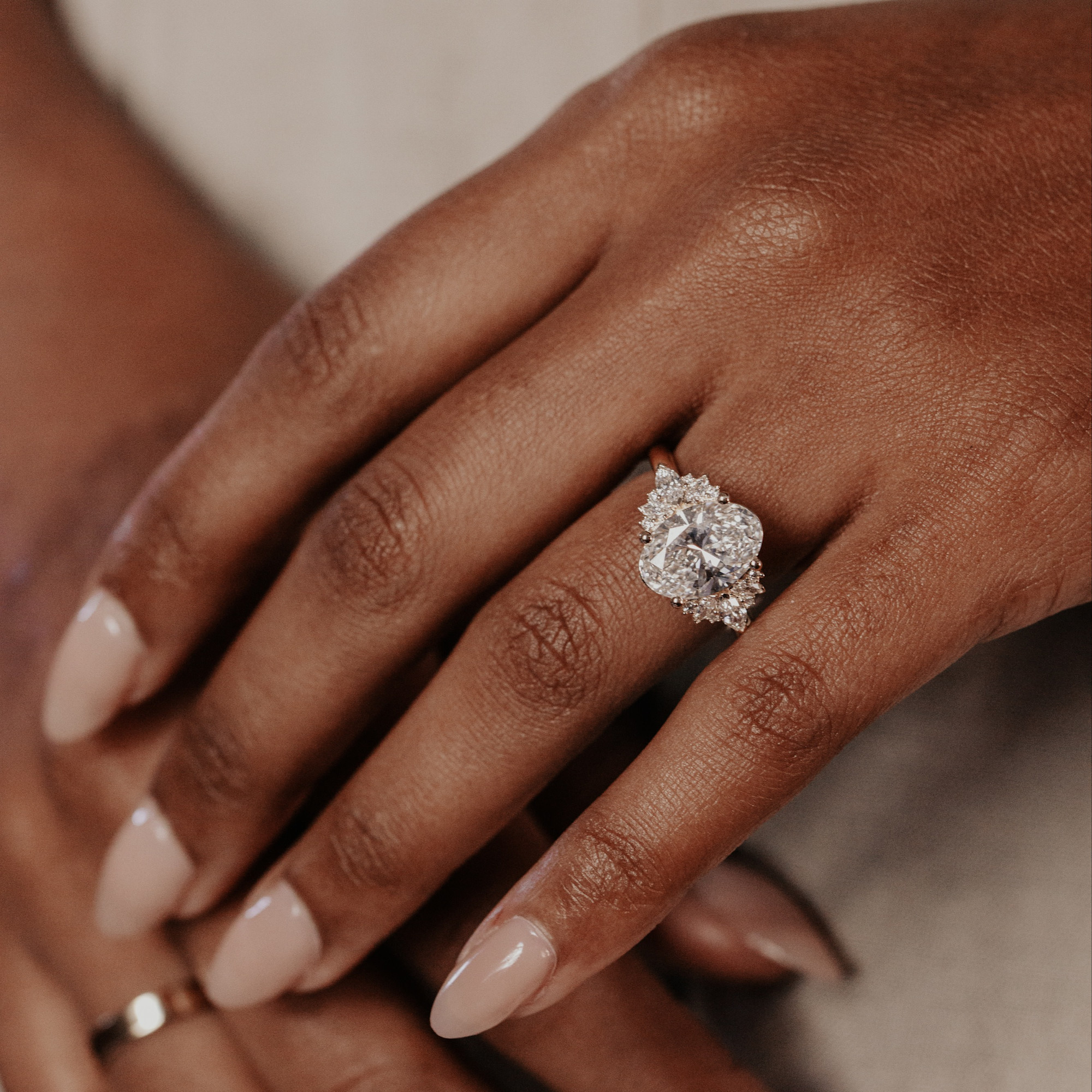Close up of a person wearing the Rita oval diamond engagement ring with diamond side stones.