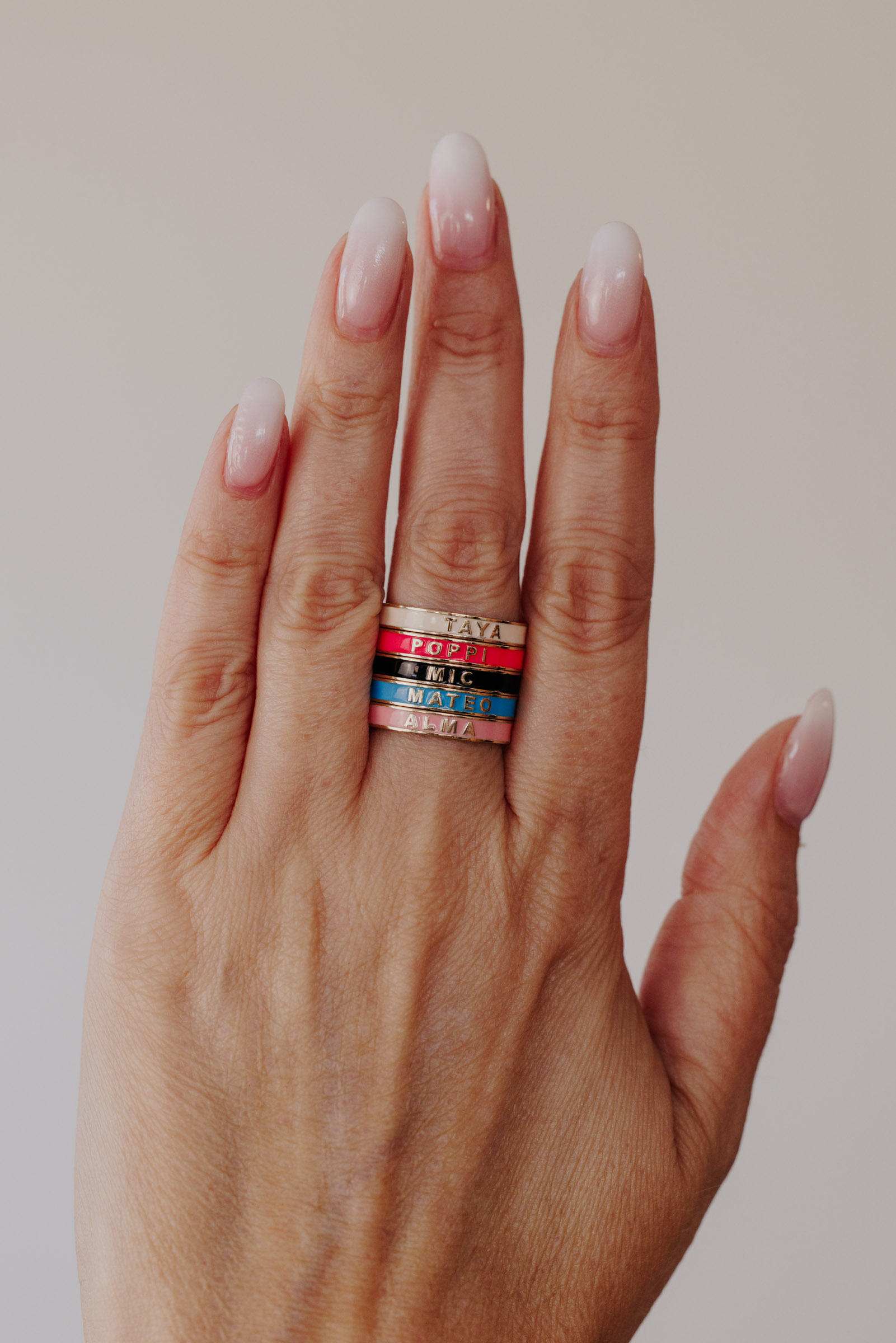 Enamel Customizable rings in different colors on a models hand.