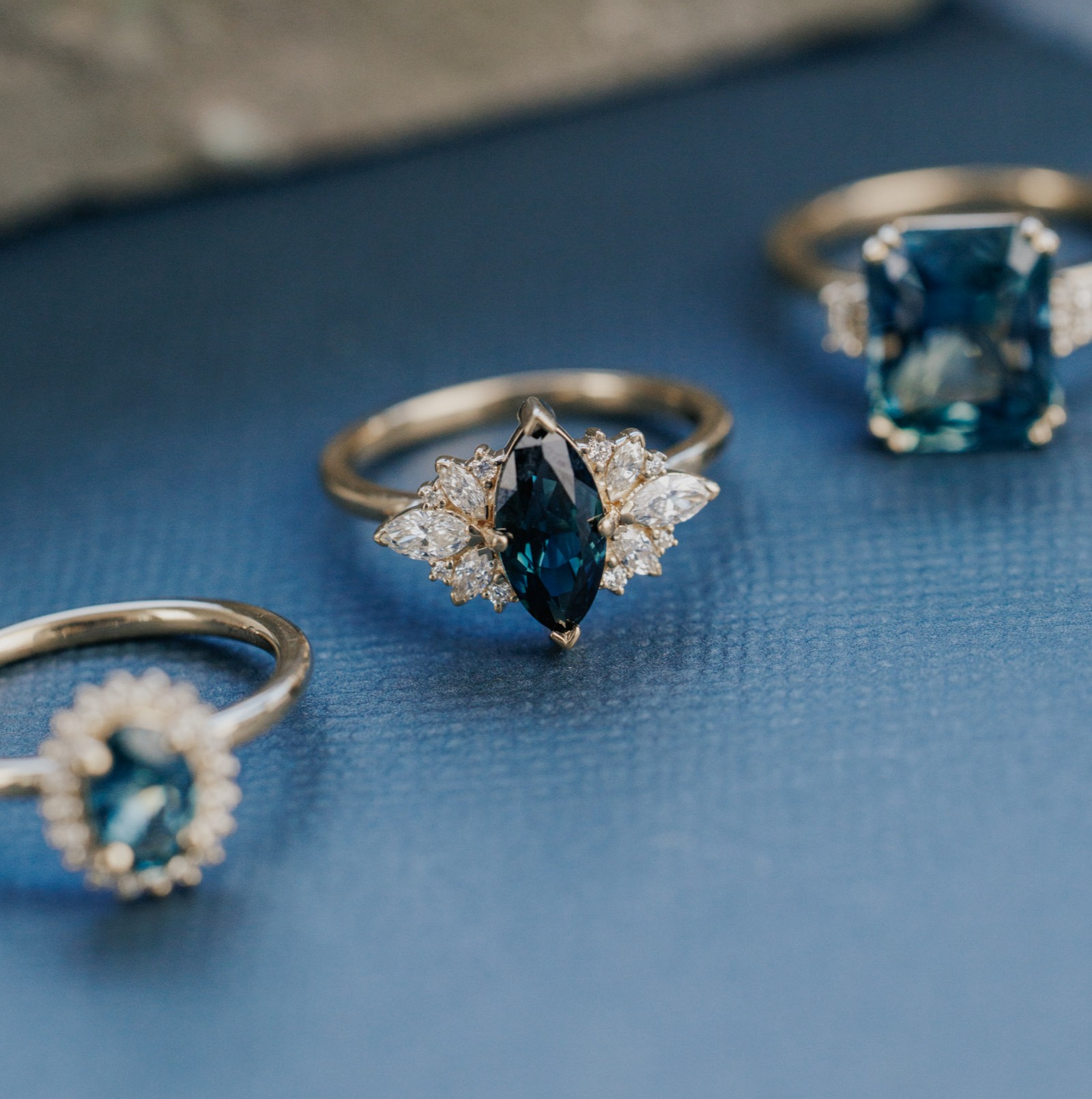Three sapphire rings from the Voyage collection on a blue background.