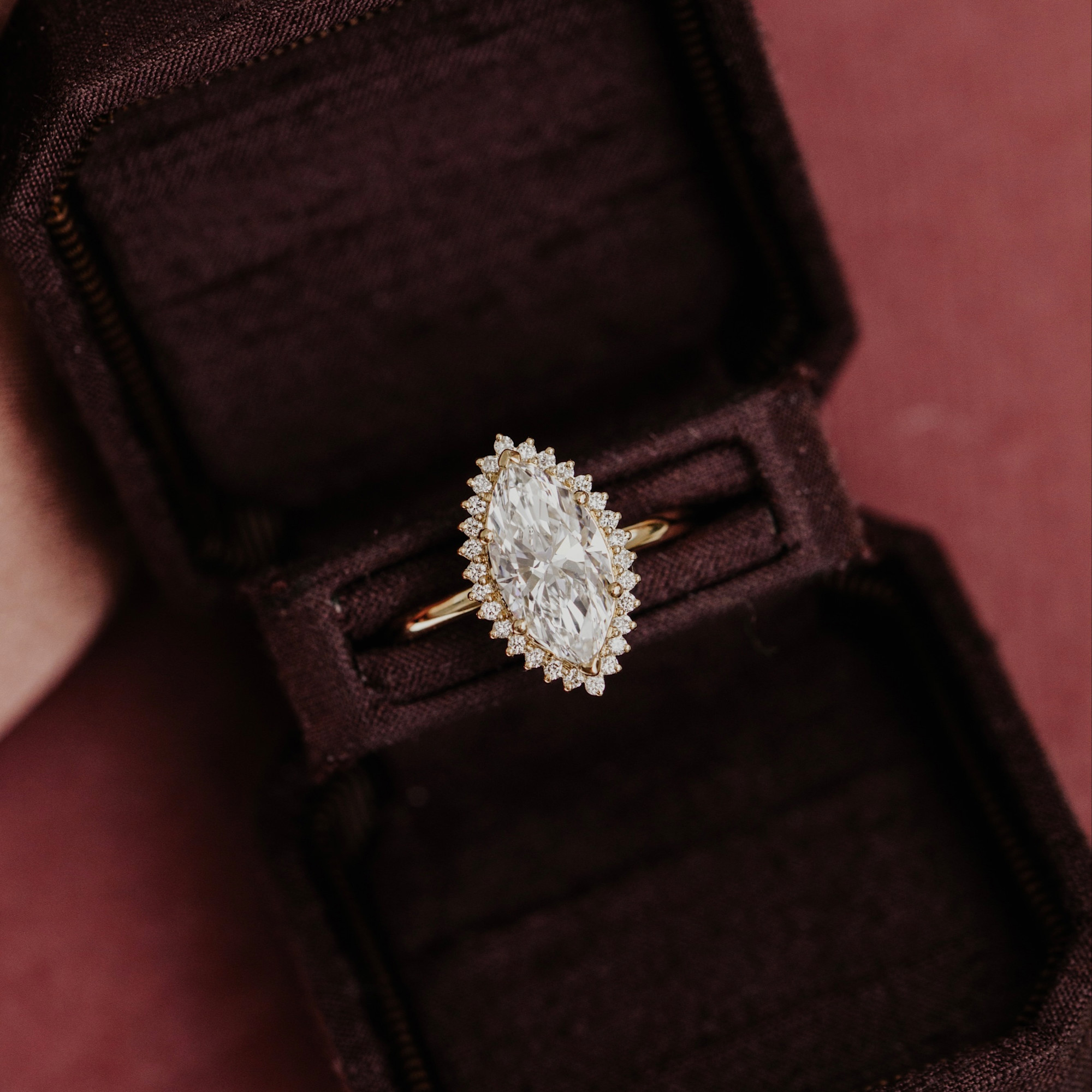 The Nova marquise diamond engagement ring with a round diamond halo placed in a deep brown velvet ring box.