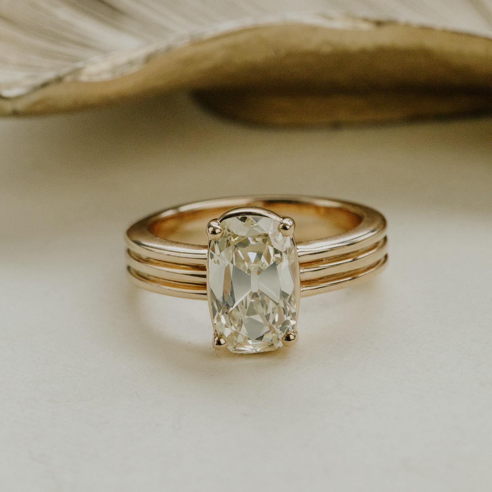 14k yellow gold ring with a 2.05 ct elongated old mine cut natural diamond with a ridged triple band on a white surface.