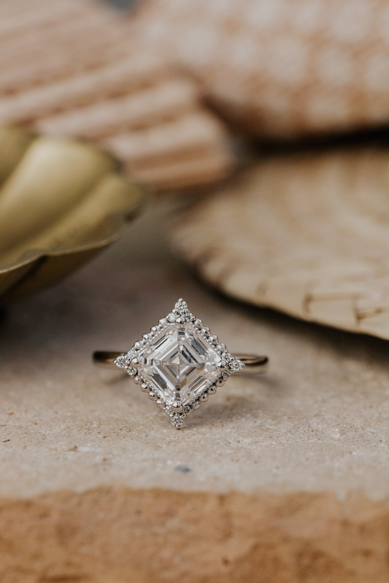 The Aurora Asscher Cut Ring in 14k white gold on a brown surface.