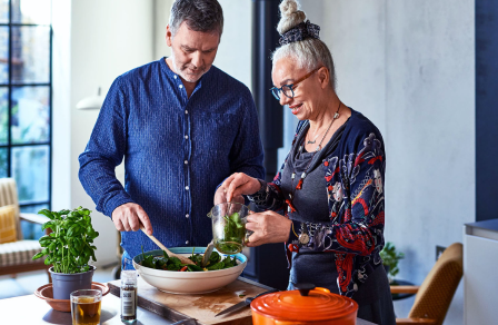 a couple making a salad in their kitchen