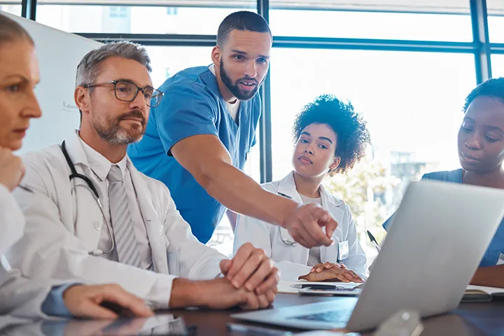 small group workspace with clinical researchers working on a laptop.